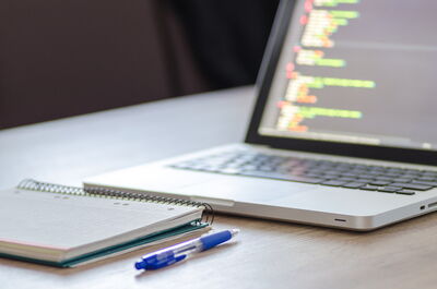Augeklapptes Notebook auf Schreibtisch, Schreibblock, Stift